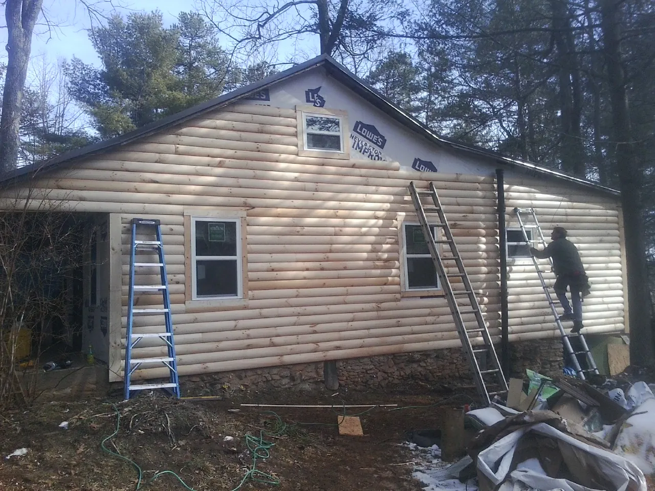 Ladders set against fresh log siding during an exterior remodel in Oakland